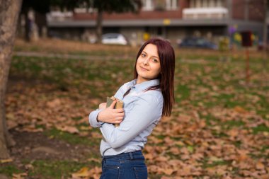 Kızıl saçlı kız ayakta ve bir kitap park holding