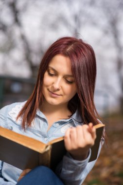 Merdivenlerde oturan ve bir kitap okuma Kızıl saçlı kız