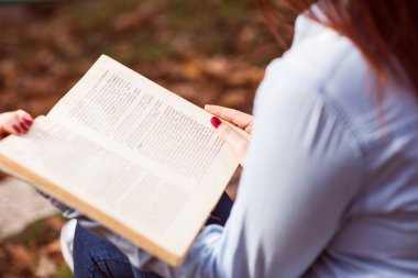 Merdivenlerde oturan ve bir kitap okuma Kızıl saçlı kız