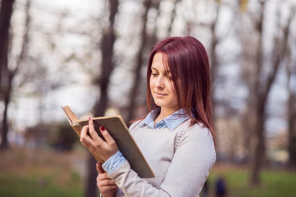 Universitet girl i park läser en bok — Stockfoto