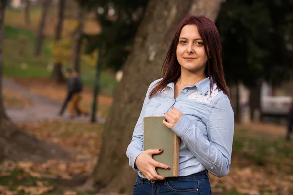 Redhead student girl holding a book in park — Stock Photo, Image