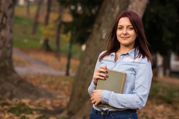 Redhead student girl holding a book in park — Stock Photo, Image