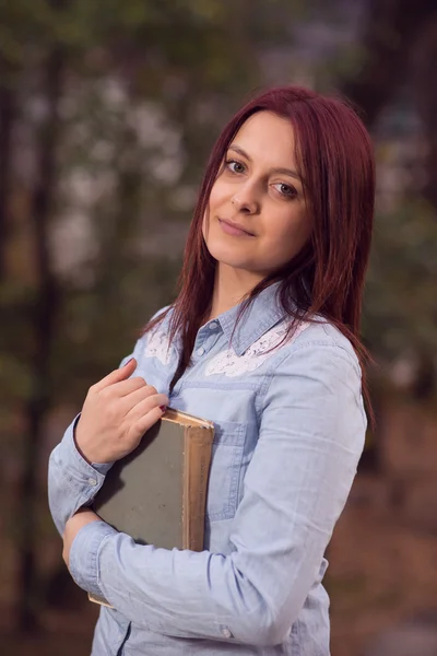 Rödhårig student tjej poserar på trappan med en bok — Stockfoto