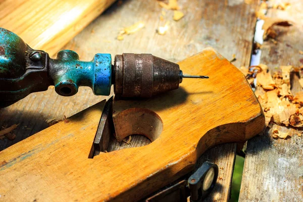 Trapano a mano, piano di falegnameria e trucioli di legno si trovano sul tavolo in falegnameria — Foto Stock
