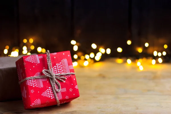 Noël, cadeaux de nouvel an sur une table en bois léger avec guirlande lumières — Photo