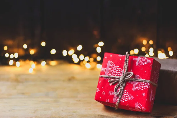 Cadeau du Nouvel An rouge noué à la ficelle sur fond de lumières jaunes. Thème de Noël. — Photo