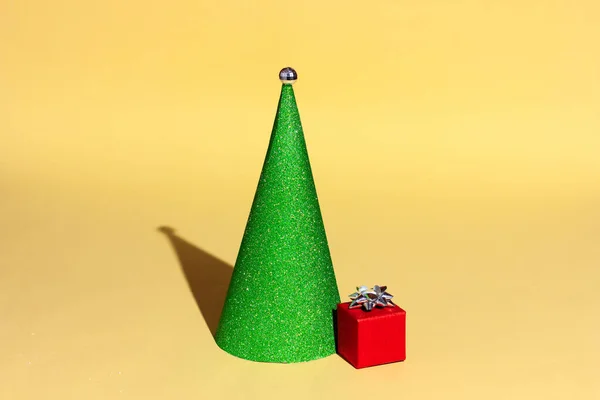 Presente vermelho e árvore de Natal verde em um fundo amarelo. — Fotografia de Stock