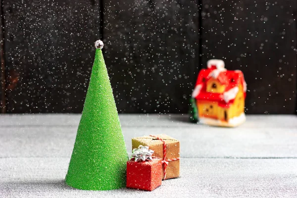 Árvore verde de Natal na forma de um cone no fundo de uma casa acolhedora, noite de Ano Novo em uma queda de neve. — Fotografia de Stock