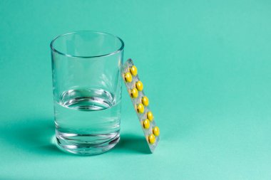 İlaçlar, haplar ve bir bardak su. Su toplamış sarı haplar..