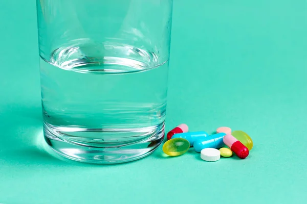 Vitamine, antidolorifici, antibiotici e un bicchiere d'acqua. Prodotti farmaceutici — Foto Stock