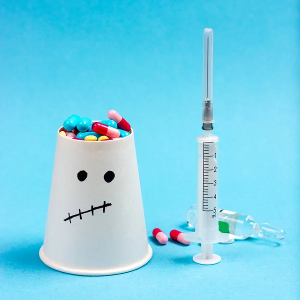 Jeringa, pastillas médicas, pastillas y un paciente sobre un fondo azul. El tema de la faccinación. Prevención de enfermedades. Vacunaciones infantiles — Foto de Stock