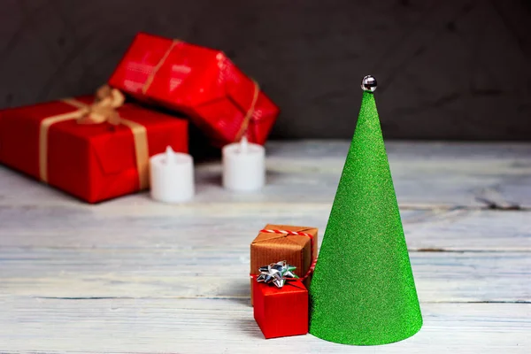 Árvore de Natal verde na forma de um cone com presentes vermelhos em uma mesa de madeira leve. — Fotografia de Stock