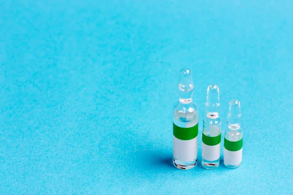 Mavi arka planda üç ampul farklı boyutlarda. Aşı kullanımı, ilaç kullanımı.. — Stok fotoğraf
