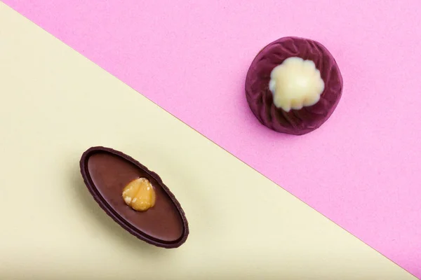 Due cioccolatini su uno sfondo diagonale giallo rosa. — Foto Stock