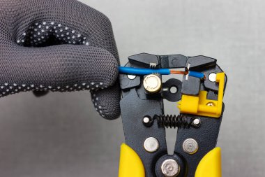 Gri iş eldiveni giyen bir elektrikçi bir striptizciyle elektrik tellerini söküyor..