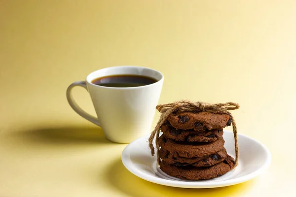Čokoládové sušenky s šálkem kávy na žlutém pozadí. — Stock fotografie
