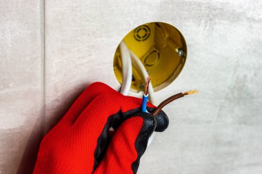 Kırmızı eldivenli adam elektrikli çıplak tel tutuyor. Ev elektrikçisi