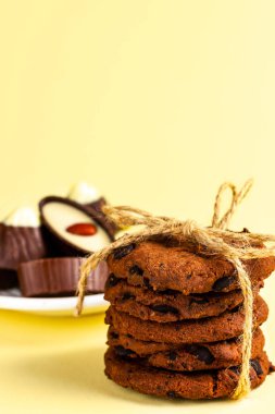 Sarı arka planda sicimle bağlanmış çikolatalı kurabiyeler..