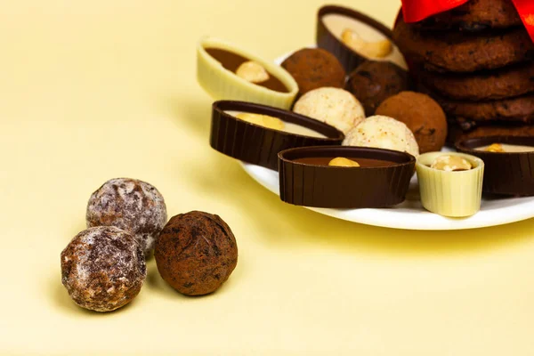 Tartufi di cioccolato e cioccolatini con noci su sfondo giallo. — Foto Stock