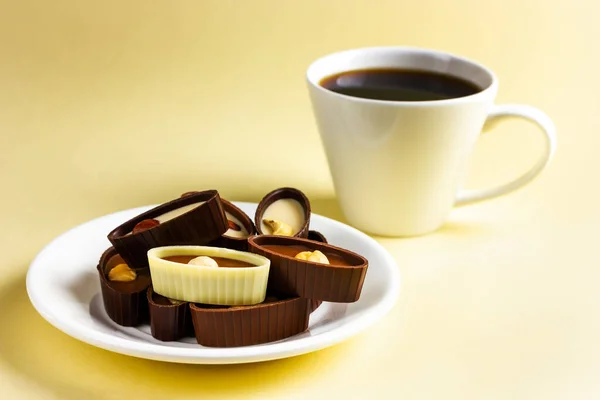 Talíř s čokoládou a šálek kávy na žlutém pozadí. — Stock fotografie