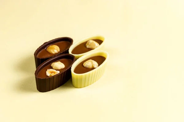 Caramelle al cioccolato con mandorle e nocciole su fondo giallo. — Foto Stock