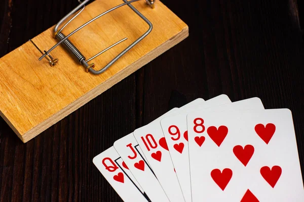 Kort på ett träbord, i bakgrunden en musfälla. Poker hand kunglig flush. — Stockfoto