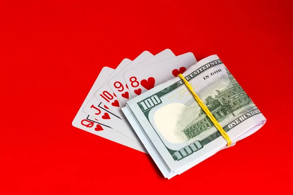 Money and cards on a red background. A combination of playing cards royal flush. — Zdjęcie stockowe