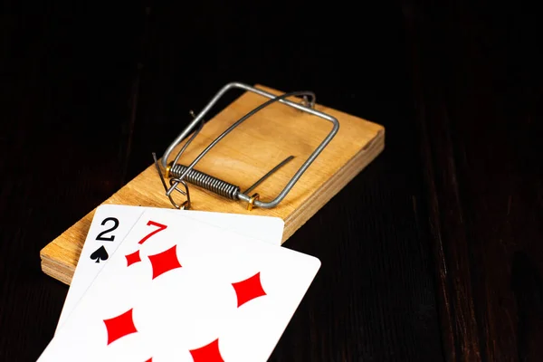 Bad playing cards lie in a wooden mousetrap on a dark wooden background. Bad luck, bad luck, in the game. Losing poker. Gambling addiction. — Stockfoto