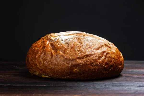 Rundes Schwarzbrot auf einem dunklen Holztisch. Rustikaler Stil. Frisch gebackenes Schwarzbrot. — Stockfoto