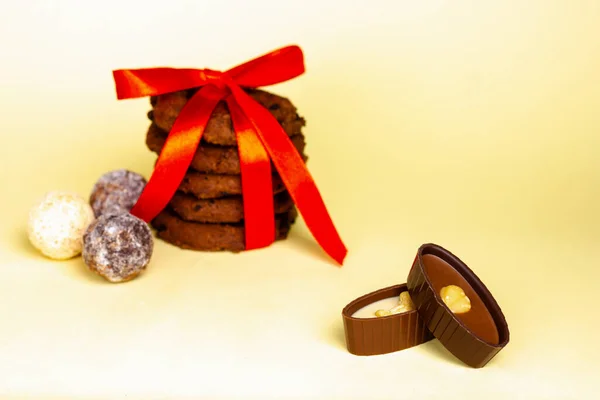 Biscotti al cioccolato e cioccolatini su sfondo giallo. — Foto Stock