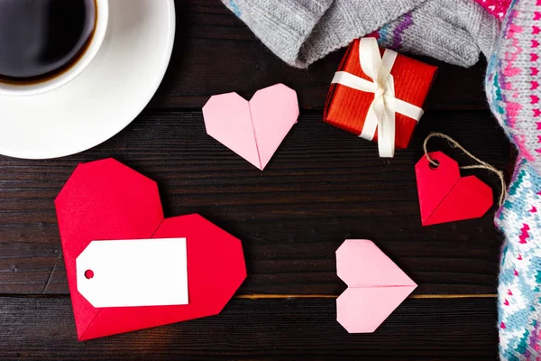 Ετοιμάζω ένα δώρο για την Ημέρα του Αγίου Βαλεντίνου. Κόκκινες καρδιές, ένα φλιτζάνι καφέ και ένα μικρό κόκκινο δώρο δεμένο με λευκή κορδέλα. Θέα από ψηλά. Θέση για το μήνυμά σας. Συγχαρητήρια για την ημέρα του Αγίου Βαλεντίνου. — Φωτογραφία Αρχείου
