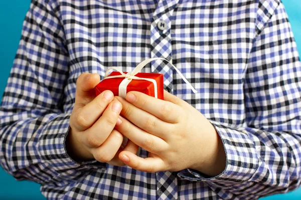 El chico tiene un regalo rojo en sus manos. Dar regalos. Felicidades por las vacaciones. Regalo de cumpleaños. Feliz día de San Valentín saludos. — Foto de Stock