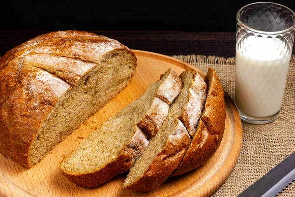 Roggenbrot und ein Glas Milch auf einem dunklen Holztisch. Frühstück auf dem Land. Rustikales Scheibenbrot. — Stockfoto