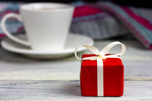 Petit cadeau rouge avec un ruban blanc sur une table en bois clair. Joyeuses salutations de Saint-Valentin. Cadeau d'anniversaire. Félicitations à un être cher. — Photo