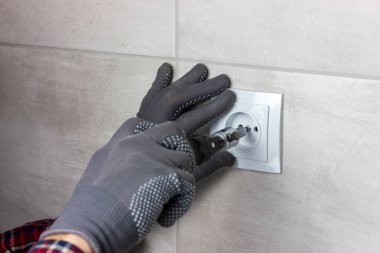 Bir elektrikçi elektrik prizi takıyor. Ev elektrikçisi tamiri.