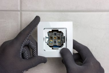 Elektrik prizi kurma süreci. Gri eldivenli erkek eller beyaz bir gül diker..