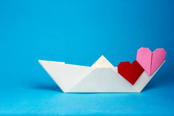 Λευκό χάρτινο σκάφος και δύο καρδιές σε μπλε φόντο. Το θέμα του ρομαντισμού, αγάπη. — Φωτογραφία Αρχείου