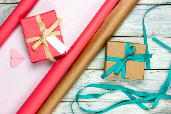 종이를 찢고 선물을 주고 나무로 된 가벼운 탁자 위에 테이프를 싸 놓고. 명절 선물 준비하기. 위에서 바라본 경관. — 스톡 사진