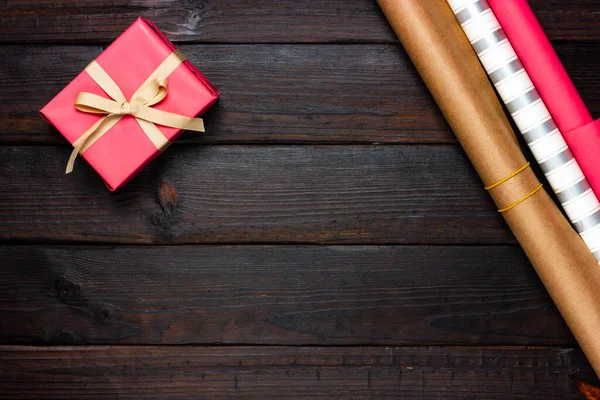 Cadeau rose et papier d'emballage sur un fond en bois foncé. Vue d'en haut. — Photo