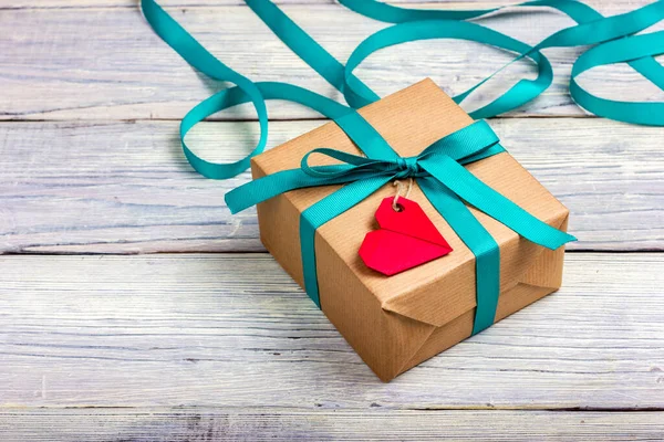 Kağıda sarılı bir hediye kutusu ve kırmızı kalp şeklinde bir kart.. — Stok fotoğraf