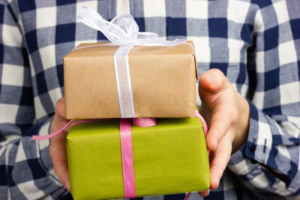 Uma rapariga de camisa xadrez tem caixas de presente. Parabéns ao seu ente querido em um feriado. Dando presentes. — Fotografia de Stock