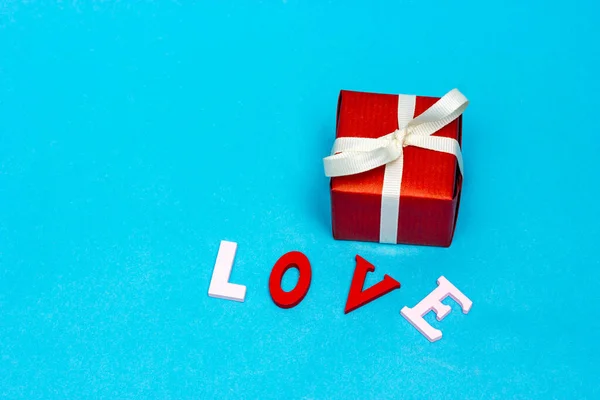 Κόκκινο δώρο με λευκή κορδέλα και η επιγραφή αγάπη. Ένα δώρο για ένα αγαπημένο πρόσωπο. — Φωτογραφία Αρχείου