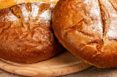 Tahta bir masada iki somun taze çavdar ekmeği. Kırsal ev yapımı ekmek pişirme