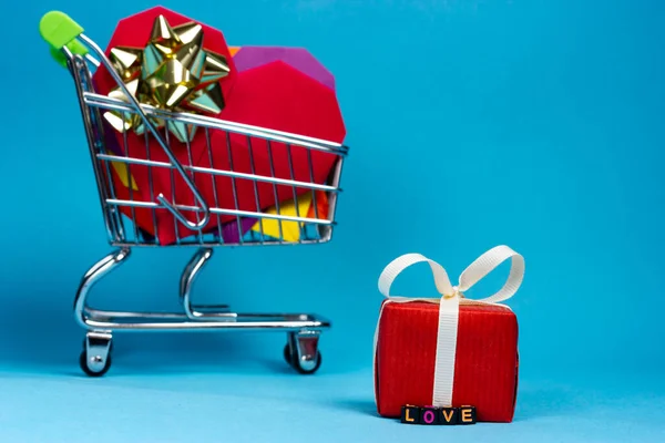 En vogn full av julegaver og en liten, rød gave med inskripsjonen kjærlighet. – stockfoto
