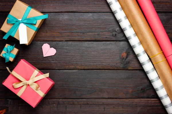 Festive Flat Lay. Caixas de presente e papel de embrulho em uma mesa de madeira escura. Empacotamento de presentes. Lugar livre. — Fotografia de Stock