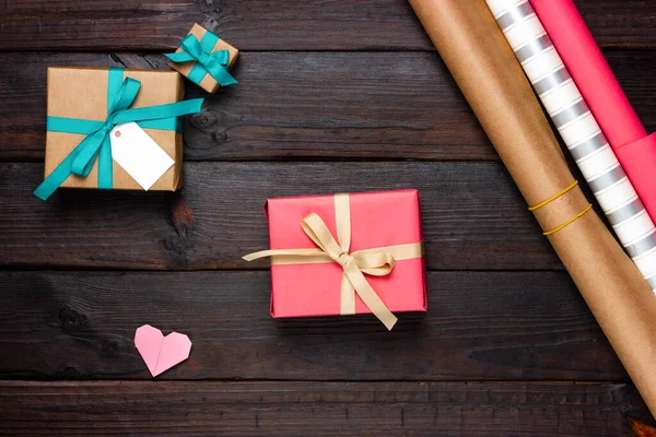 Várias caixas de presente, papel de embrulho e corações de papel em uma mesa de madeira escura. Festivo, romântico Flat Lay — Fotografia de Stock