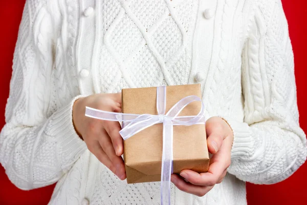 A menina está segurando um presente em papel artesanal e com uma fita branca. Dar presentes. Processo de parabéns. — Fotografia de Stock