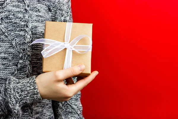 A menina segura uma caixa de presente com uma fita branca nas mãos. Parabéns pelo feriado. Lugar para publicidade. — Fotografia de Stock