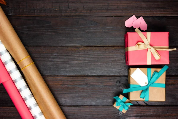 Gift boxes and wrapping paper on a dark wooden table. Festive Flat Lay. Gift wrapping process.