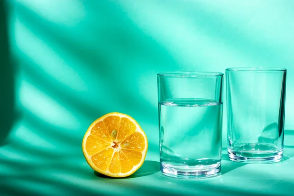 Стакан питьевой воды и пол свежего лимона. Вода в стакане. Солнечный свет из окна. — стоковое фото